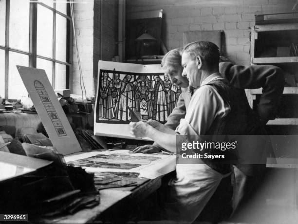 Liddall Armitage, chief designer, and Arthur Howe, head glass cutter, working on a scene from the coronation being recreated in stained glass for the...
