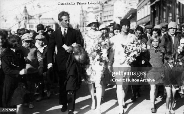 Prince Leopold , later King Leopold, and his wife Astrid walk in the streets of Ostende surrounded by a crowd of well-wishers.