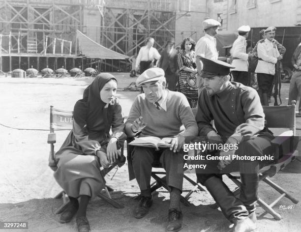 Director Edwin Carewe , centre, consults with actors Lupe Velez and John Boles prior to a take for the Universal film 'Resurrection'. Carewe had...