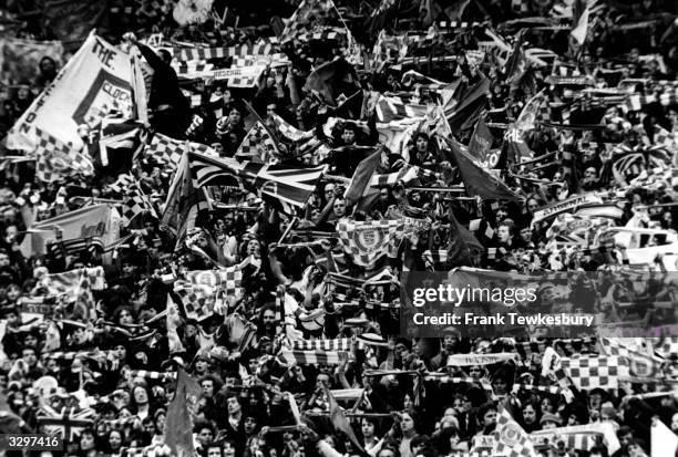 Arsenal fans wave their scarves and banners at Wembley Stadium.