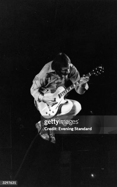 Pete Townshend, songwriter and guitarist of the British rock band The Who, seen in flight, whilst playing with the band on stage in 1975.