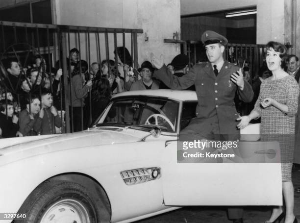 Fans watch as German TV celebrity Uschi Siebert presents American rock 'n' roll star Elvis Presley with the keys to the BMW sports car with which...