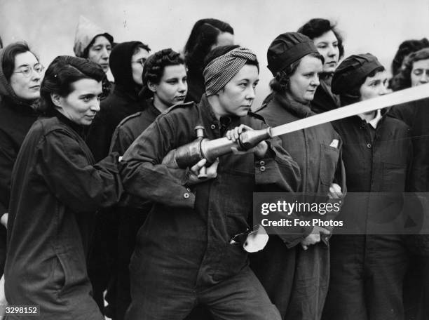 Female civil servants demonstrate the correct stance for holding a fire hose during training at the Imperial War Museum Fire Fighting School.