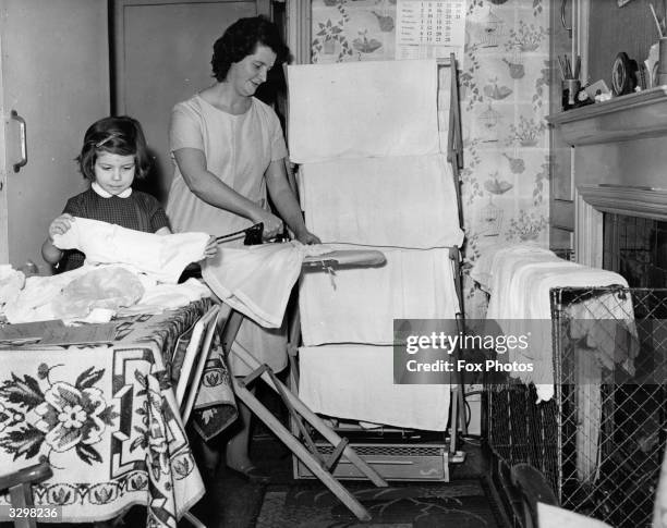 Mrs June Fowler, a mother of triplets at the ironing whilst her elder daughter Susan helps her fold clothes.