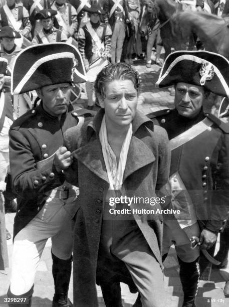 Ronald Colman , the British romantic actor who left for Hollywood in 1920, is being led to the guillotine by two soldiers in a scene from 'A Tale of...