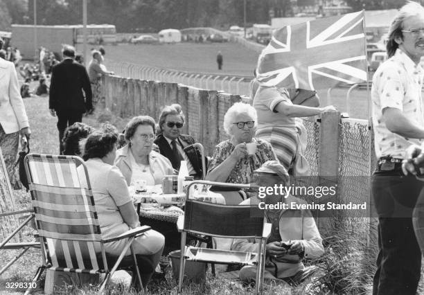 Picnic party settles down by a fence on Derby Day at Epsom race course.