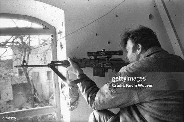 Serbian sniper fires through a window in Brcko, North Eastern Bosnia.