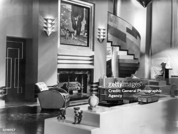 The art deco interior of a house which serves as the set for the film 'Our Modern Maidens', with a sweeping staircase leading from the lounge area....
