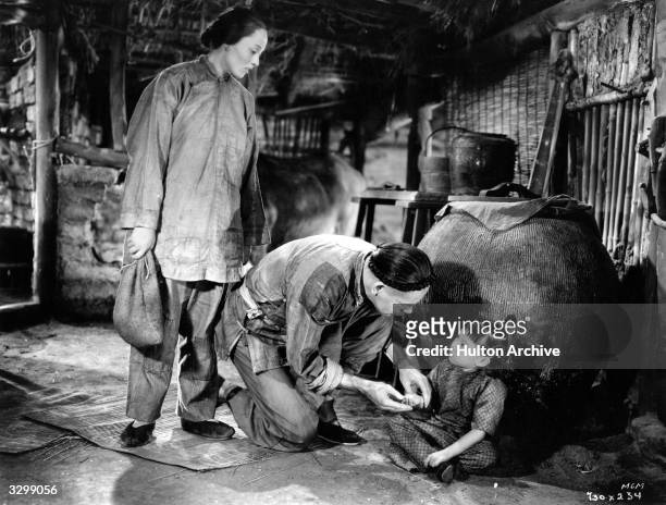 Luise Rainer and Marcella Wong star with Paul Muni in a scene from the film 'The Good Earth'.