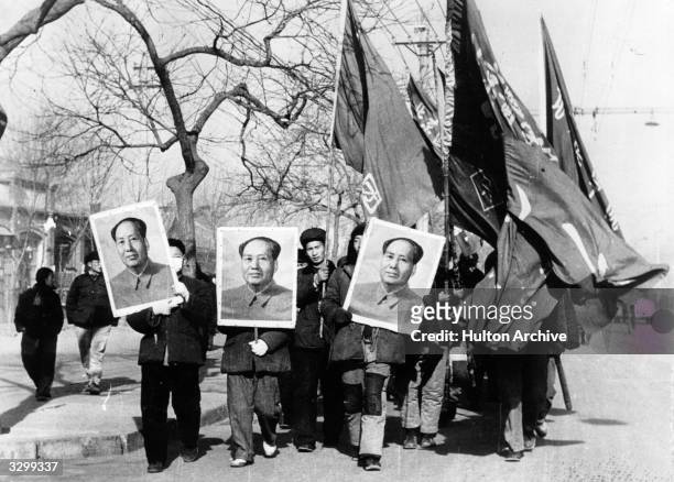 Members of the Red Guards carry large portraits of Mao Tse Tung as they parade through the streets of Peking .