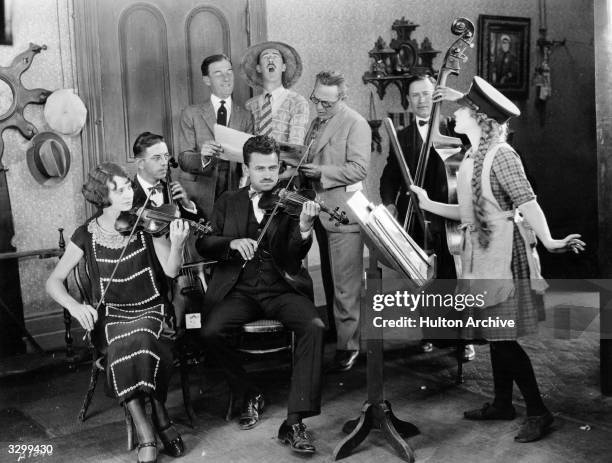 Actress Mary Pickford formerly Gladys Smith, directs her orchestra and singing trio in a rendering of 'Little Annie Rooney'. From left to right, the...