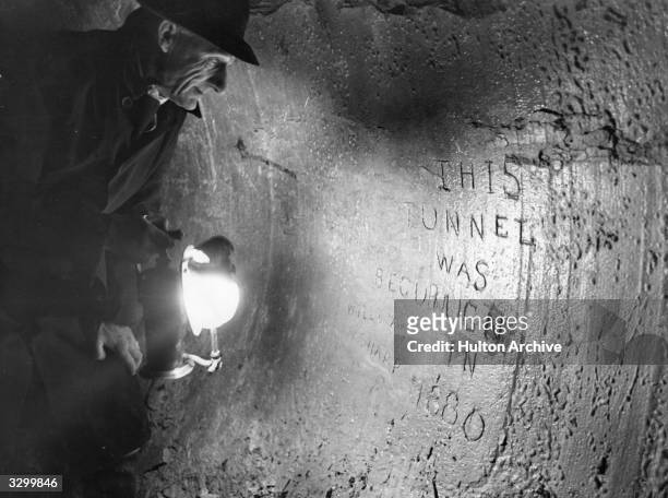 Man inspects the inscription on the pilot tunnel of the 1880 Channel Tunnel project.