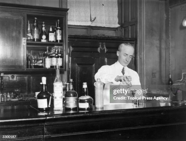 American barman Harry Craddock expertly mixes a drink in the American bar of the Savoy Hotel in London. Author of 'The Savoy Cocktail Book', Craddock...