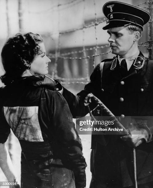 Concentration camp officer threatens Margaret Lockwood with a whip in a scene from the 20th Century Fox film 'Gestapo', aka 'Night Train to Munich'....