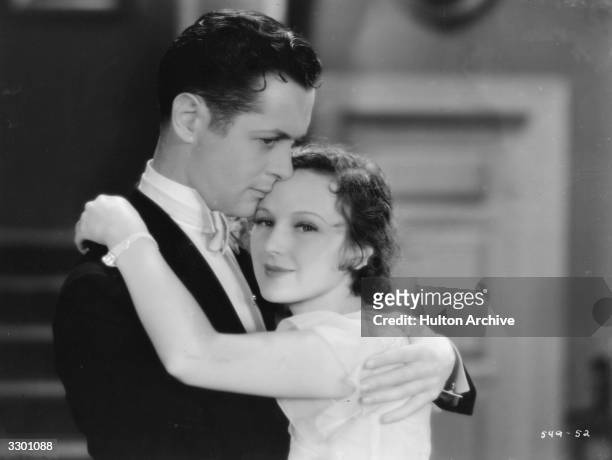 Actors Dorothy Jordan and Robert Montgomery share a romantic moment in the film 'Shipmates', directed by Harry A Pollard for MGM.