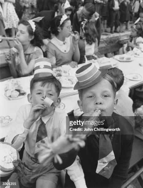 Couple of East End boys blowing paper whistles at a street party held in Morpeth Street, London, during Queen Elizabeth II's Coronation celebrations....