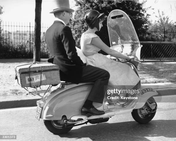 Couple on their way to the races at Ascot by scooter.