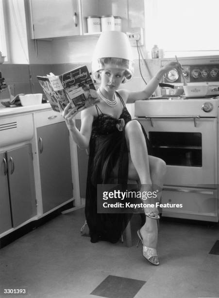 Film actress Barbara Roscoe does the cooking in her spotless kitchen as she waits for her hair to set.
