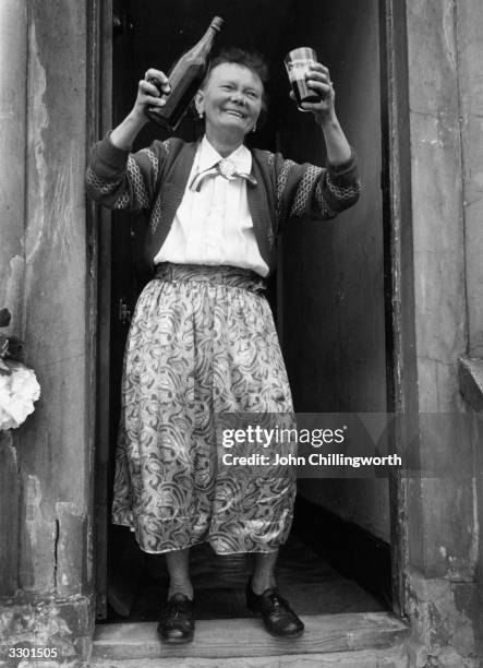 Resident of Morpeth Street in the East End of London enjoys a glass of stout at a street party to celebrate the coronation of Queen Elizabeth II. The...