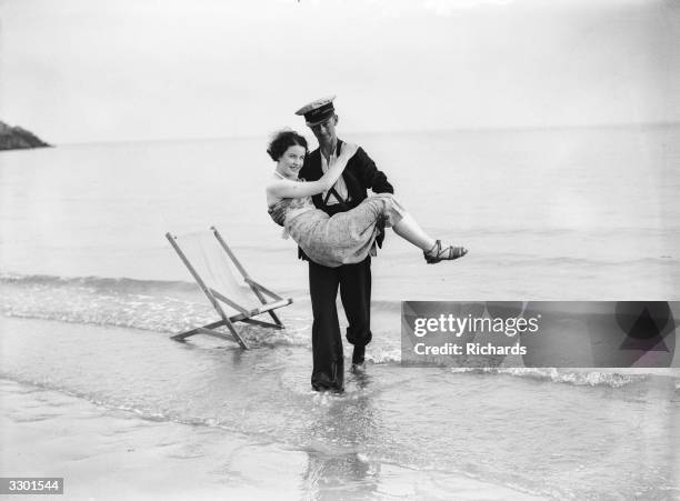 Young lady falls asleep on the beach and has to be rescued from the advancing tide by a gallant deckchair attendant at Barry Island, South Wales.