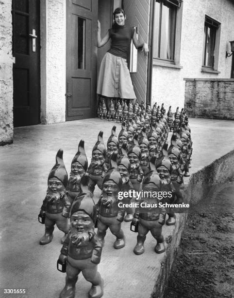 An army of German garden gnomes on parade outside a house.