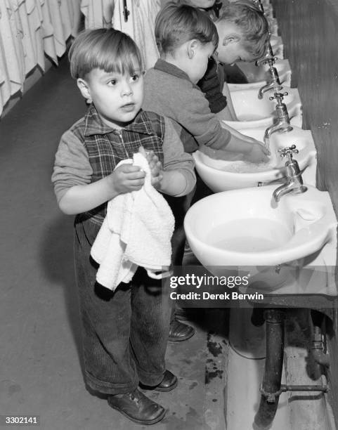 Group of boys washing and drying their hands in the scaled down sinks at the Sumner Nursery Centre in Peckham, London.