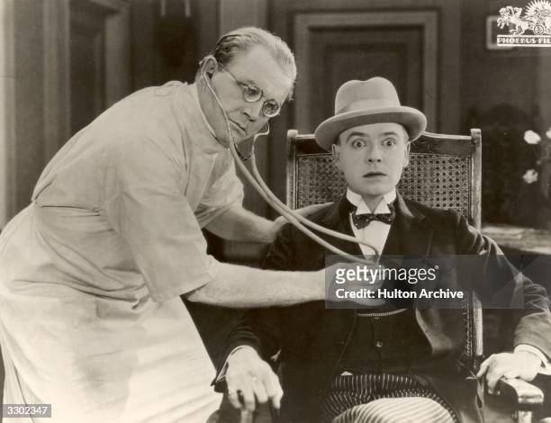 Doctor listens to the rhythm of a patient's heart in a scene from the German silent film 'Komodie des Herzens', directed by Rochus Gliese.