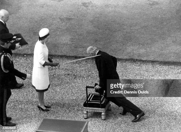 Queen Elizabeth II knighting solo yachtsman Francis Chichester with the sword of Sir Francis Drake at the Grand Square in Greenwich, London.