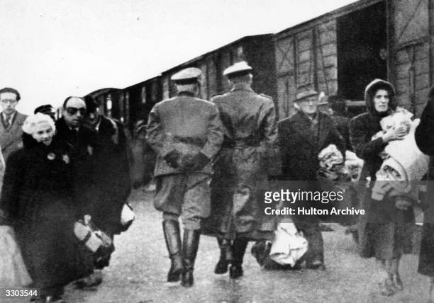 Nazi officers supervise Jews leaving railway trucks during the deportation to the camps.