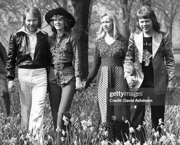 Swedish pop group Abba, winners of the 1974 Eurovision Song Contest at Brighton, strolling hand in hand amongst the daffodils in Hyde Park, London.