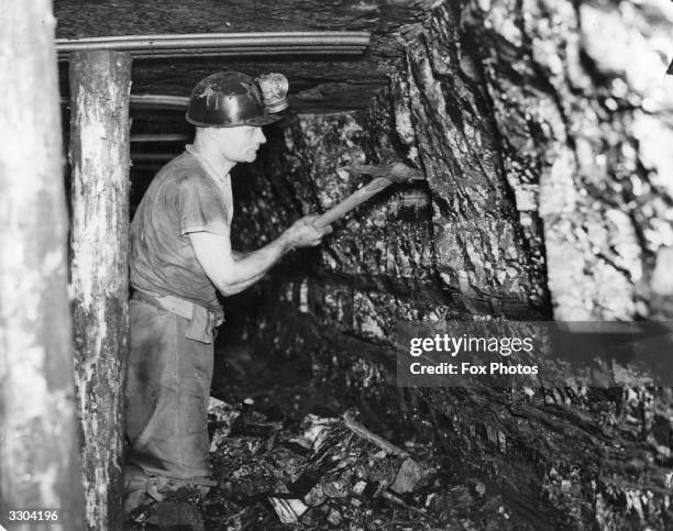 Miner at work with a pick axe at the coal face in the Ashington Coal Companies Colliery at Newcastle upon Tyne.