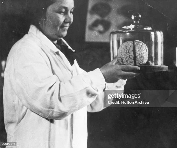 The woman in charge of the Institute for Brain Research in Moscow holds a bell-jar containing a brain.