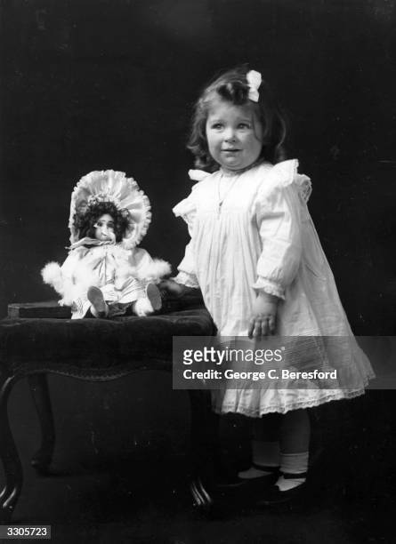 Miss Daniels, an Edwardian child, stands beside a stool.