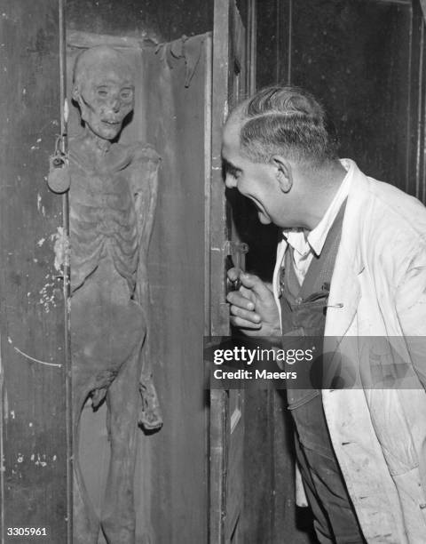 John Farwig, a workman helping with the restoration at the Wren church in St James, London, admiring the mummified man in a cupboard in the vestibule.