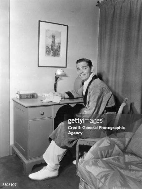 American actor Clark Gable , star of 'Gone With The Wind' reading a letter in his dressing room.