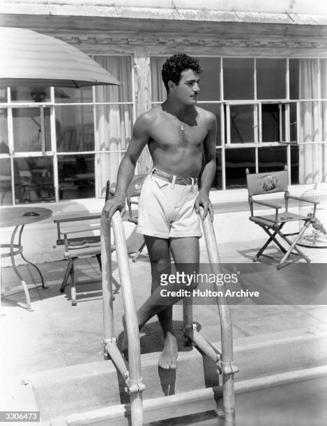 Hollywood actor Gilbert Roland poses by the steps of the swimming pool at his home. He is about to star in the United Artists talkie 'New York...