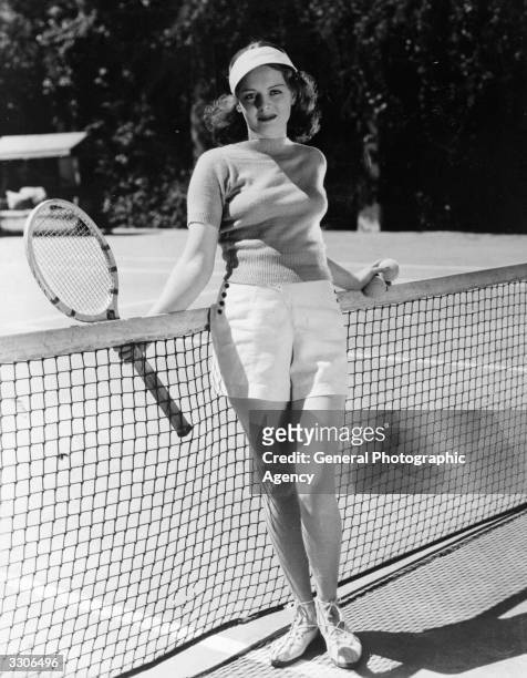 American actress Arleen Whelan posing by a tennis net.