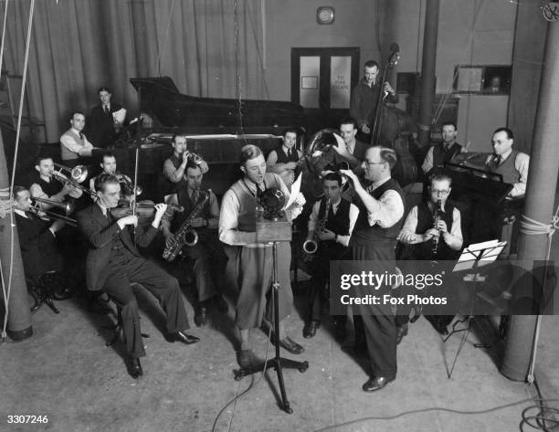 Billy Cotton sings with his dance band in a radio studio.