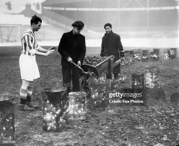 Ground staff at Stoke City tending the braziers which have been placed on the football pitch in an attempt to thaw the frozen ground. Player, Stanley...