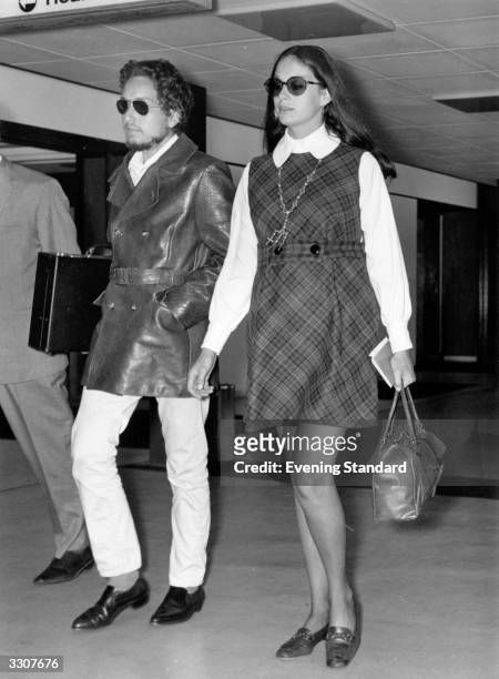 American electric folk hero Bob Dylan arriving at an airport with his wife Sara.