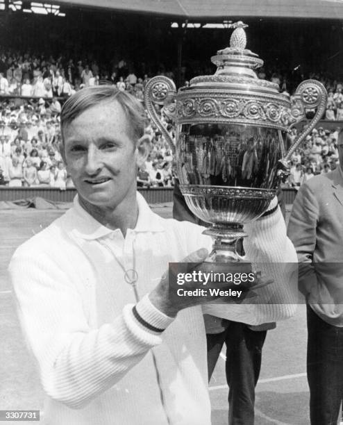 Australian tennis player Rod Laver lifts the trophy after beating Tony Roche of Australia in the men's singles final at Wimbledon.
