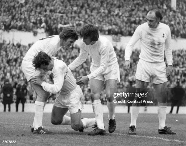 Alan Mullery of Tottenham Hotspur is helped up by team-mates Martin Peters , Cyril Knowles and Alan Gilzean , after being injured when scoring Spurs'...