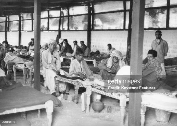 An overcrowded emergency smallpox ward in Karachi, with an earth floor, corrugated iron roof and rudimentary furnishings, during the worst outbreak...