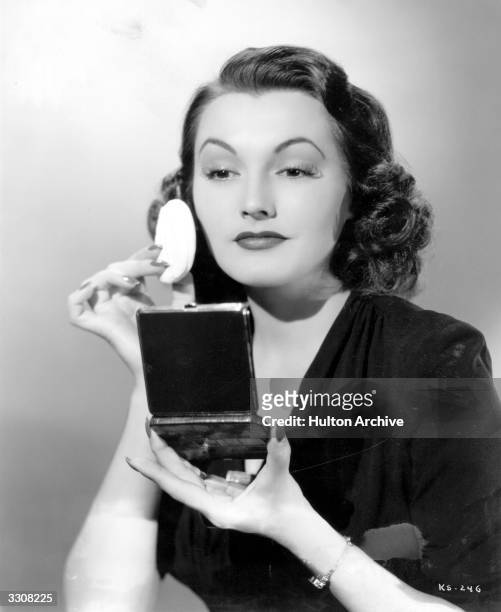 Actress Kay Sutton demonstrates the 'Beauty For The Asking' powder container, which is backed by rich alligator leather and has a mirror in the lid...