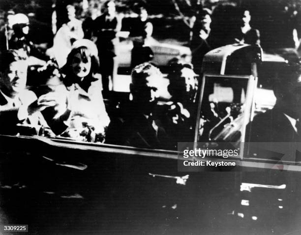 President John F. Kennedy and First Lady Jacqueline Kennedy ride with Texas Governor John Connally and others in an open car motorcade shortly before...