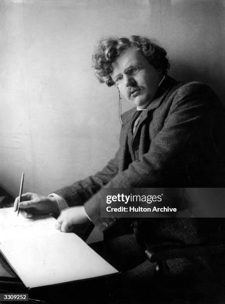 Gilbert Keith Chesterton , English novelist, at his desk.