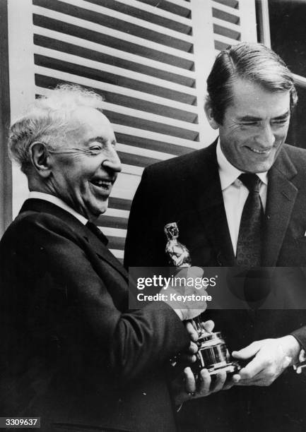 Celebrated pianist, Arthur Rubinstein, receiving the Hollywood 'Oscar' from Gregory Peck in the Parisian residence of the great musician.