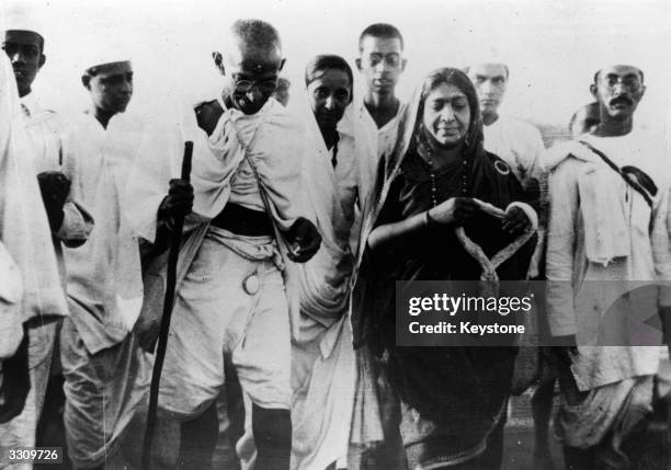 Indian nationalist leader Mahatma Gandhi , and politician Mrs Sarojini Naidu, with a garland, during the Salt March protesting against the government...