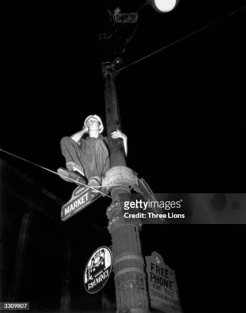 Daring young man perches on a lamppost during the VJ celebrations in the USA.