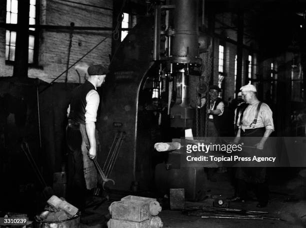 Workers smithing under a steam hammer at the Midland Railway Company's works in Derby.